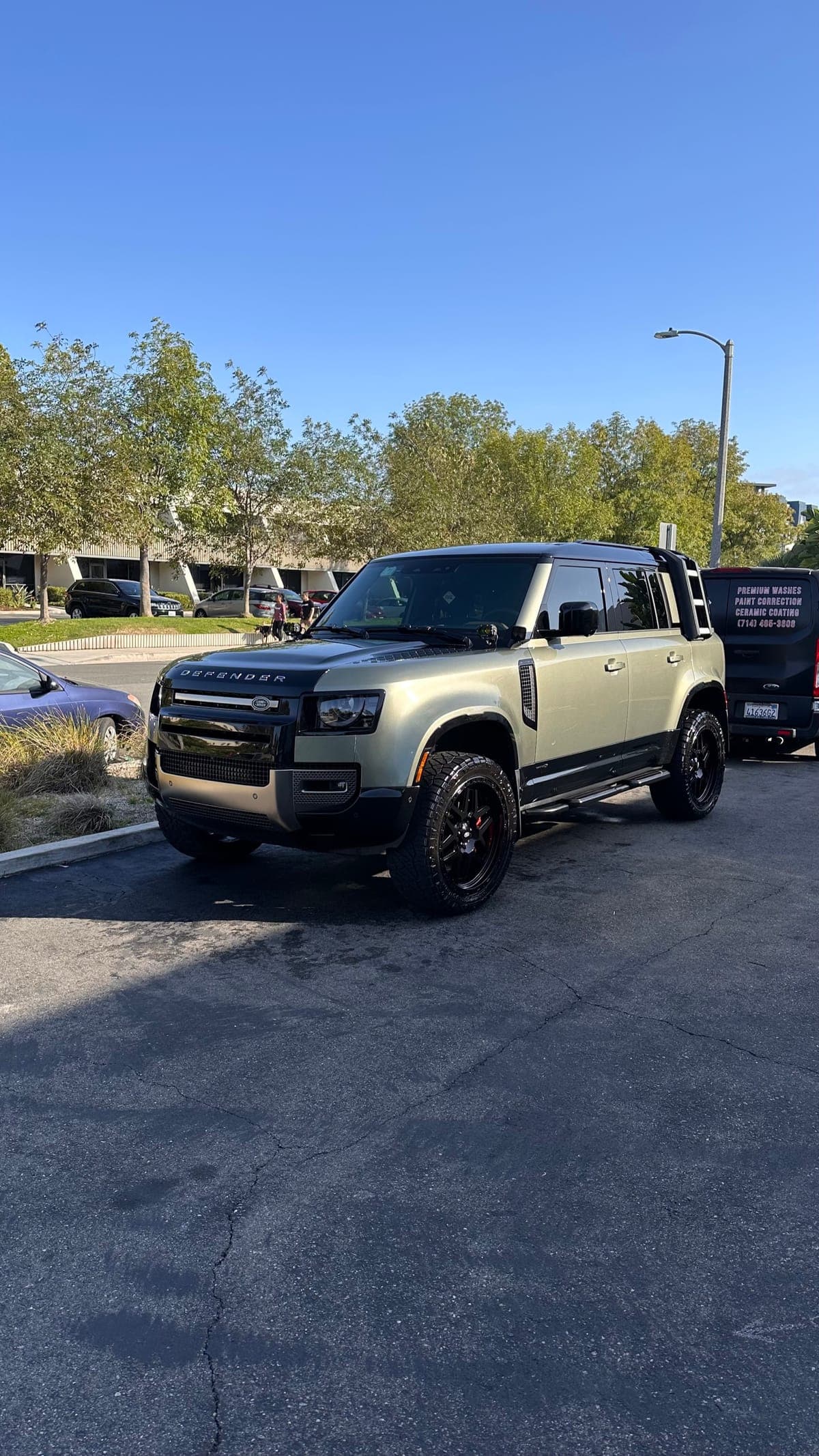Green Land Rover Defender mobile detail with van in Orange County
